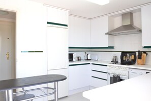 Une cuisine moderne avec des meubles blancs, une cuisinière, un four à micro-ondes et un grille-pain.