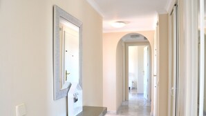A hallway with a mirror, a coat rack, and a door leading to another room.
