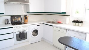 A compact kitchen with a washing machine, dishwasher, and a sink.