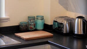Eine Küche mit einem weißen Schrank, einem Toaster, einem Wasserkocher und drei Gläsern auf der Arbeitsfläche.
