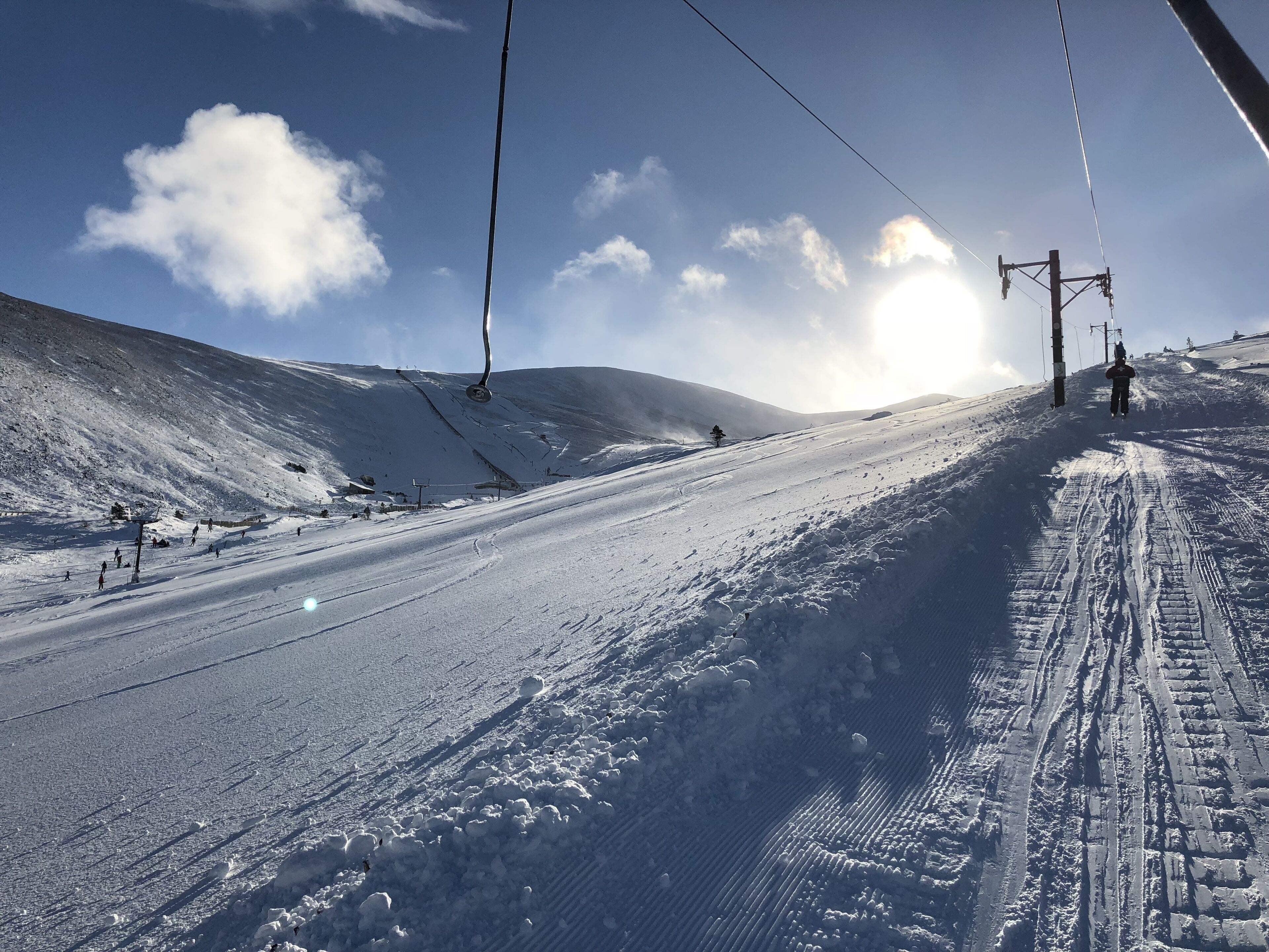 A snowy ski slope with ski lifts and tracks.