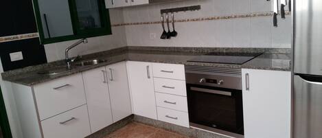A kitchen with white cabinets, a stainless steel refrigerator, a built-in oven, and a microwave.