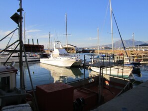 A marina with several boats docked, a clear sky, and distant mountains.