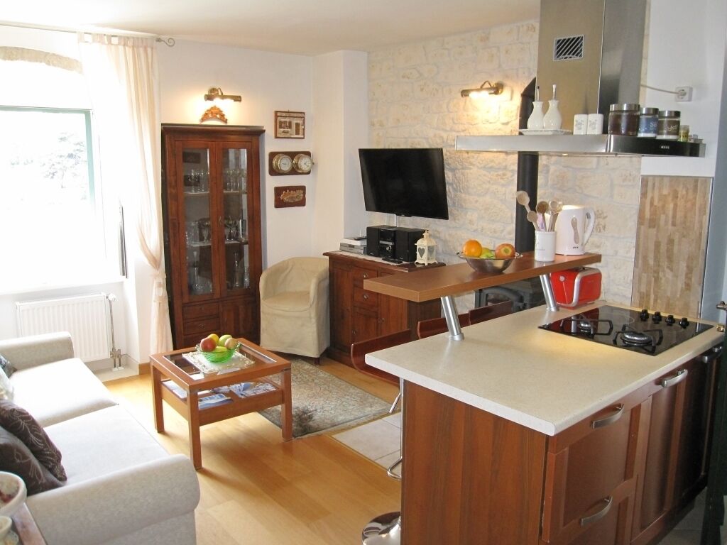 A modern kitchen with a built-in stove, wooden cabinets, and a dining area with a table and chairs.
