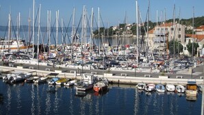 Un port de plaisance où sont amarrés de nombreux bateaux, un ciel dégagé et des bâtiments en arrière-plan.