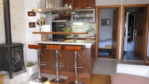 Une cuisine compacte dotée d’un îlot central, d’une cuisinière et d’un coin bar avec des tabourets.