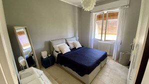 Una camera da letto con un letto grande, un comodino, uno specchio e una finestra con persiane.