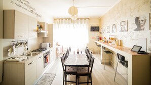 Eine moderne Küche mit Essbereich, ausgestattet mit einem langen Tisch, Stühlen und einer Küchenzeile mit Geräten.