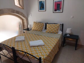 Un dormitorio con una cama, dos mesitas de noche, una lámpara, una toalla y un cuadro colgado en la pared.