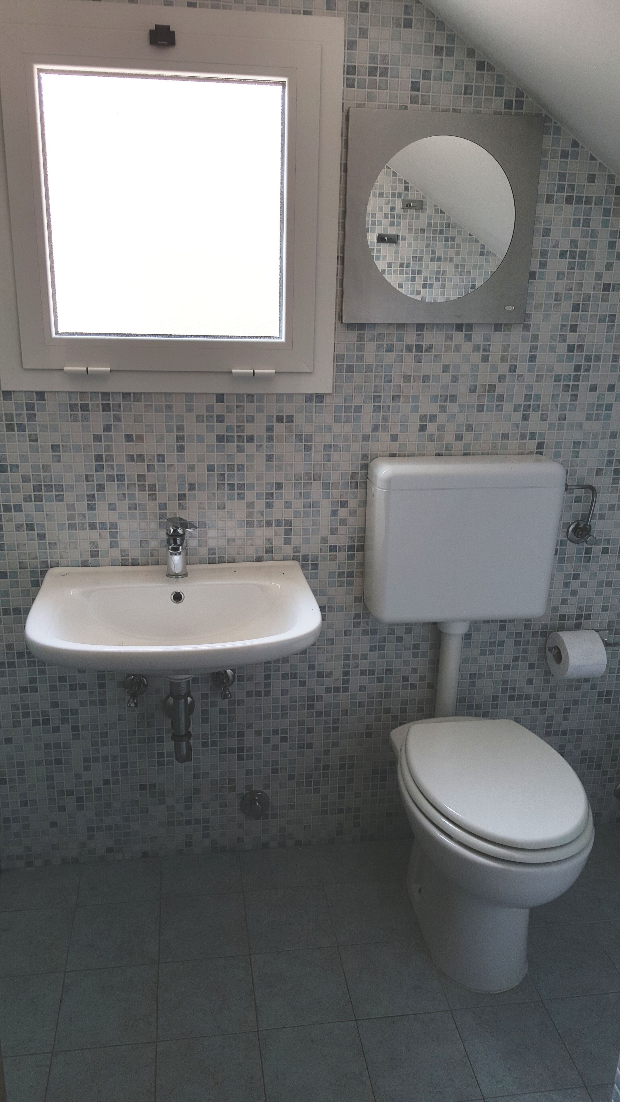 Une salle de bain avec un lavabo, des toilettes et un miroir.