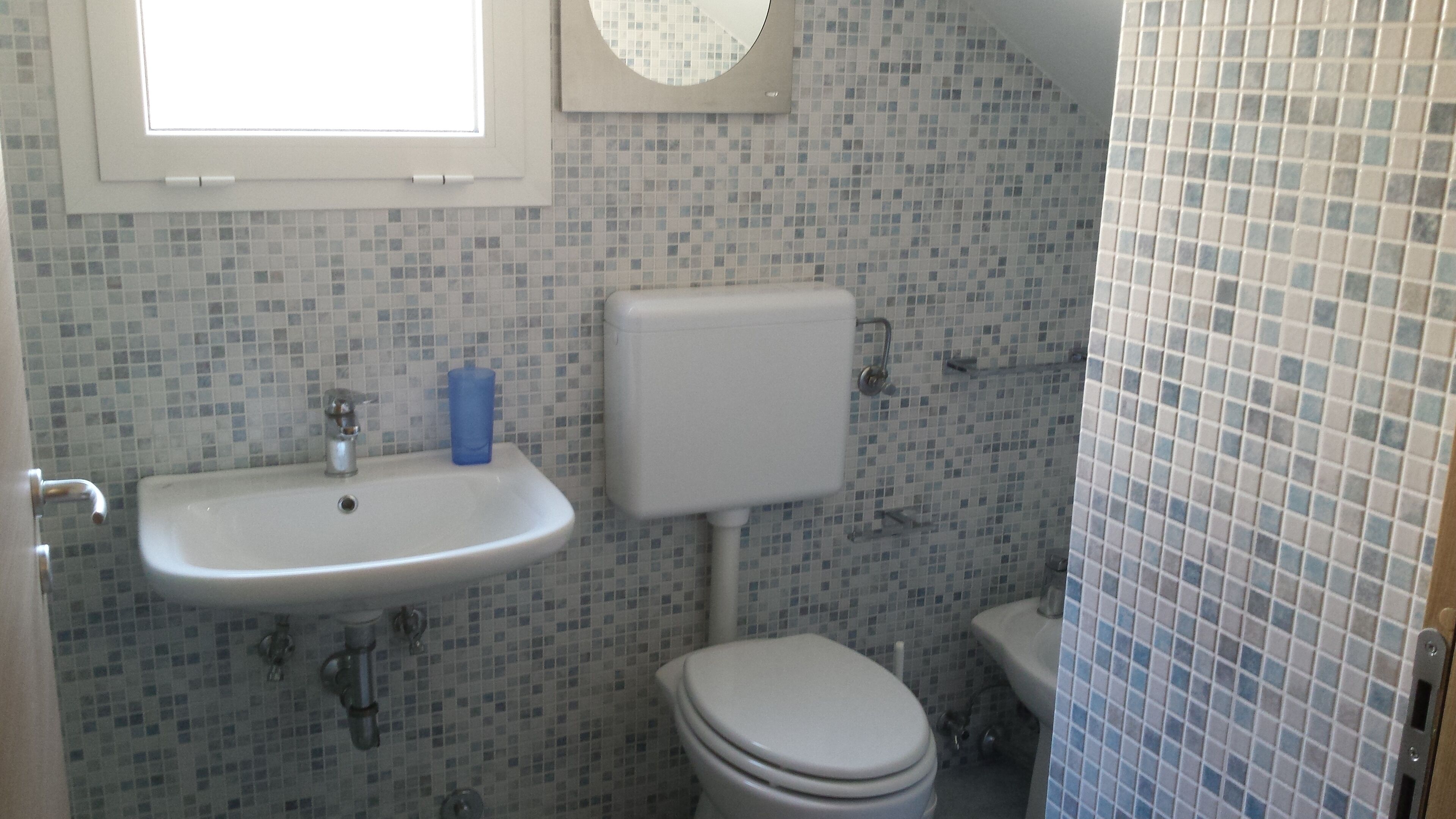 A bathroom with a sink, toilet, and a window above the sink.