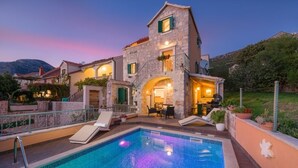 Une villa en pierre dotée d’une piscine, d’un espace extérieur aménagé et offrant une vue sur les montagnes.