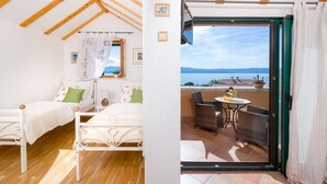 Une chambre à coucher comprenant un lit, une table de chevet et donnant sur un balcon aménagé avec du mobilier d’extérieur.