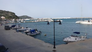 A marina with boats docked, a clear sky, and a hilly landscape in the background.
