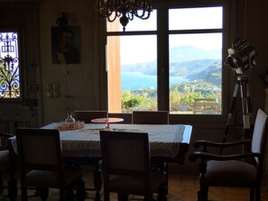 A dining area with a table set for four, a chandelier, and a view of a mountainous landscape through large windows.