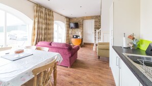 A spacious living area with a pink sofa, a dining table with a cake, and a kitchen with a sink and a television. - Bowes Barn 4 Star near Beamish, Newcastle & Durham - Sleeps 3 -  Dogs Welcome  (Gateshead)