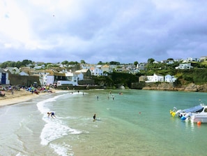 A coastal town with houses on a hillside, a sandy beach, and calm waters.