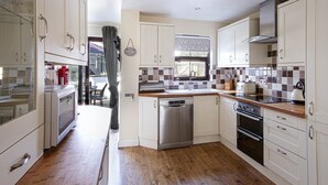 A compact kitchen with a dishwasher, oven, and a window with a view. - Flip Flops - Three Bedroom Cottage, Sleeps 6 (Crantock)