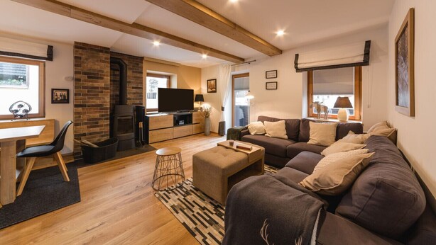 Ein gemütliches Wohnzimmer mit Kamin, Fernseher und einer großen Couch.