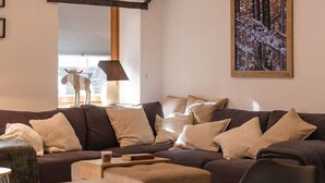 Ein gemütliches Wohnzimmer mit einer Eckcouch, einem Holzesstisch und Pendelleuchten.