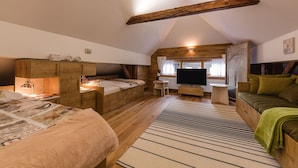 Ein gemütliches Schlafzimmer im Dachgeschoss mit einem Hochbett, einem Schreibtisch und einer Couch.