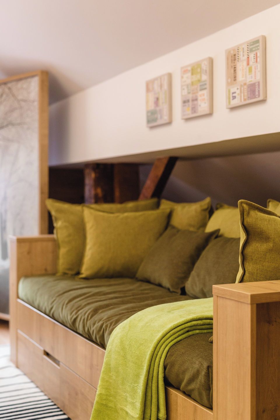 A modern bedroom with a wooden bed, green bedding, and a wall-mounted artwork.