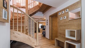 Eine Holztreppe führt zu einer oberen Etage, ein Flur mit einem Fernseher und Einbauschränken.