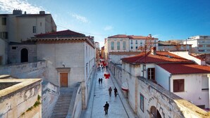 A narrow street with buildings on both sides, a staircase on the left, and a red ribbon hanging across the street. - Apartment in Zadar with Seaview, Balcony, Air condition, WIFI (858-2) (Zadar)
