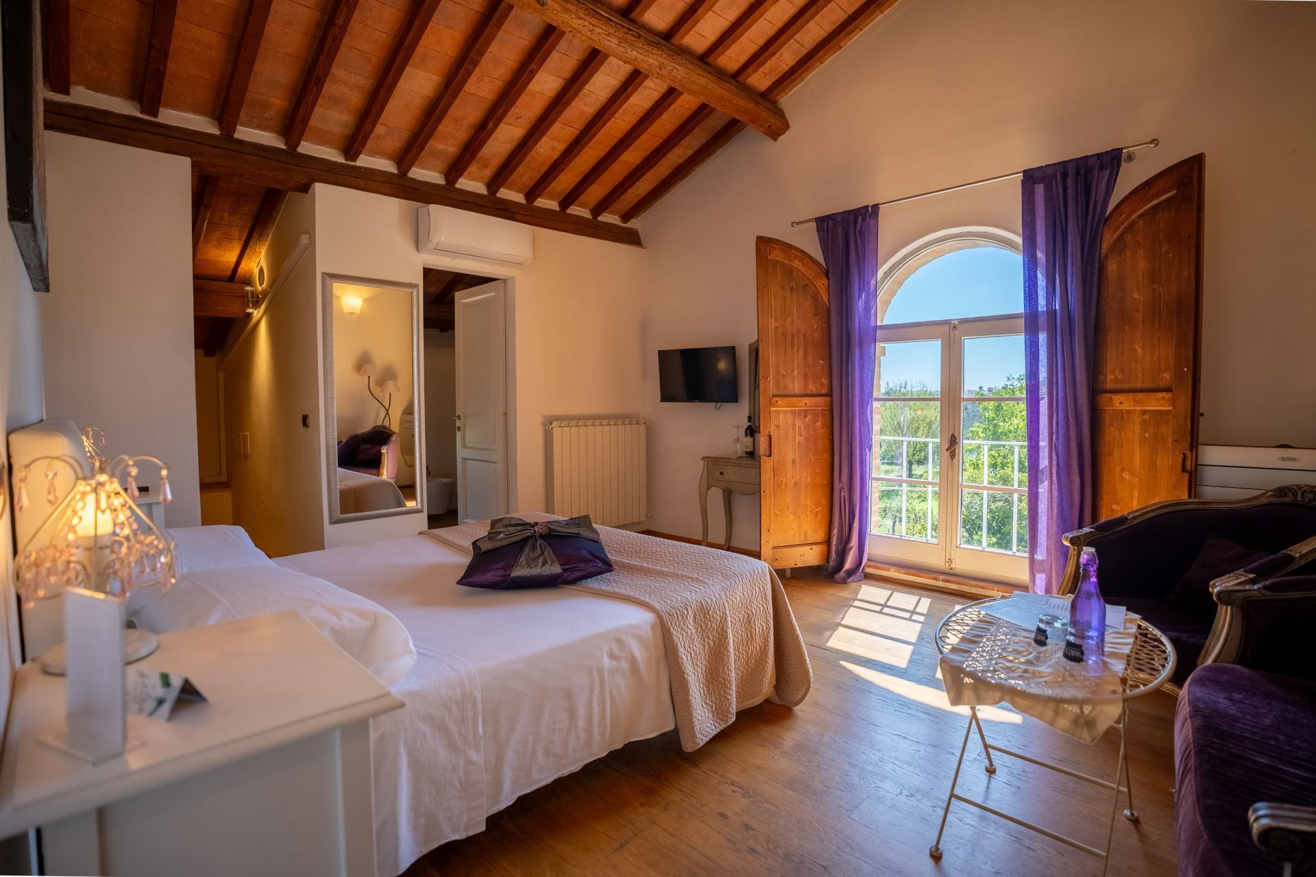Un dormitorio con cama, mesita de noche y una pequeña mesa con una botella.
