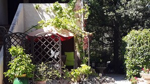 Un jardín con pérgola, plantas en macetas y un muro de piedra.
