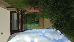 Una habitación con vista al cielo a través de un ventanal, una valla de madera y un jardín.
