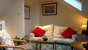 Una sala de estar acogedora con un sofá floral, una mesa de centro de madera y una silla.