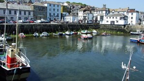Un puerto con barcos amarrados, un muro de piedra y edificios de arquitectura tradicional.