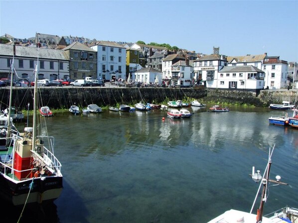 A harbor with boats docked, a stone wall, and buildings with traditional architecture. - The Cabin at Little Bosveal (Mawnan Smith)
