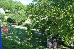 A garden with a table and chairs, surrounded by greenery and trees.