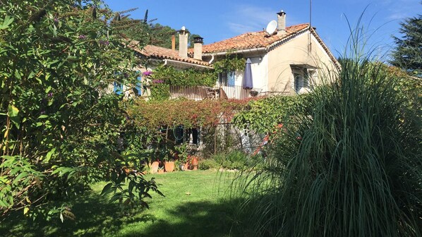 A house with a tiled roof, surrounded by lush greenery and a well-maintained garden.