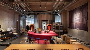 A bar area with a red counter, stools, and various bar equipment.