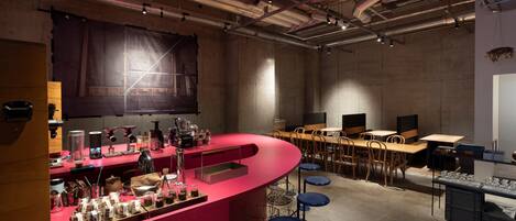 A bar area with a curved counter, stools, and a variety of bottles and glasses.