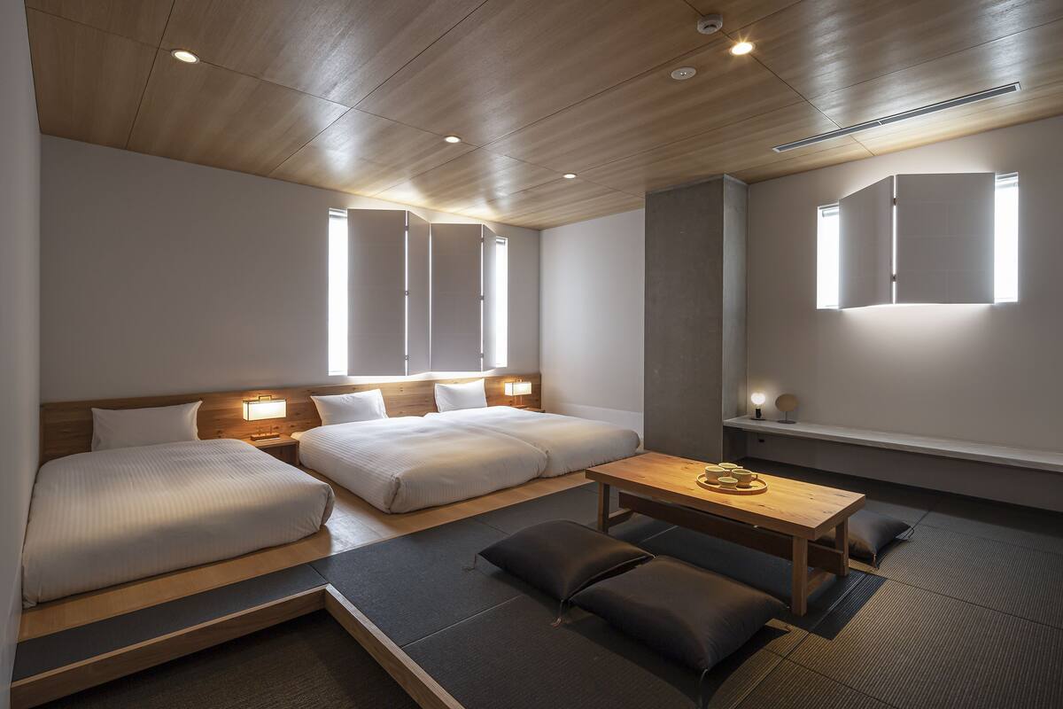 Ein Hotelzimmer mit zwei Betten, einem kleinen Tisch und einer Bank.