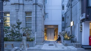 A narrow urban street with a building featuring large windows and a modern entrance.