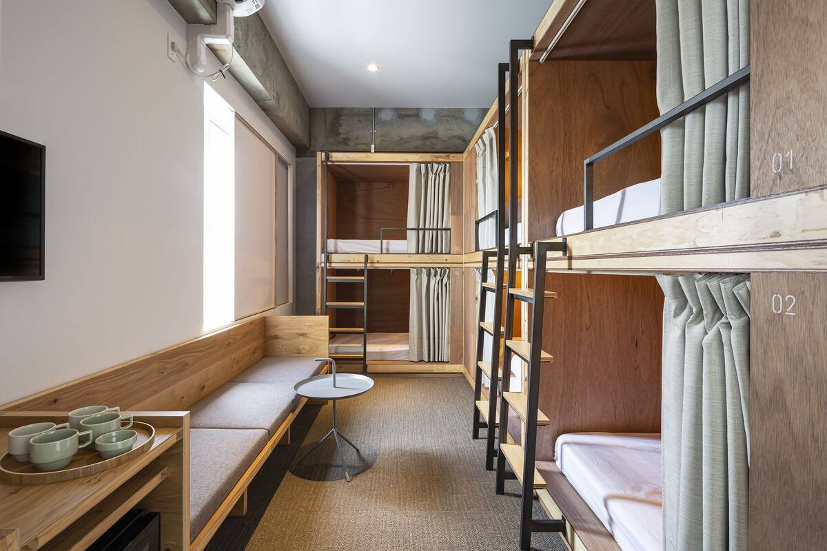 Ein kleines Zimmer mit Etagenbetten, einem Tisch und einer Bank.