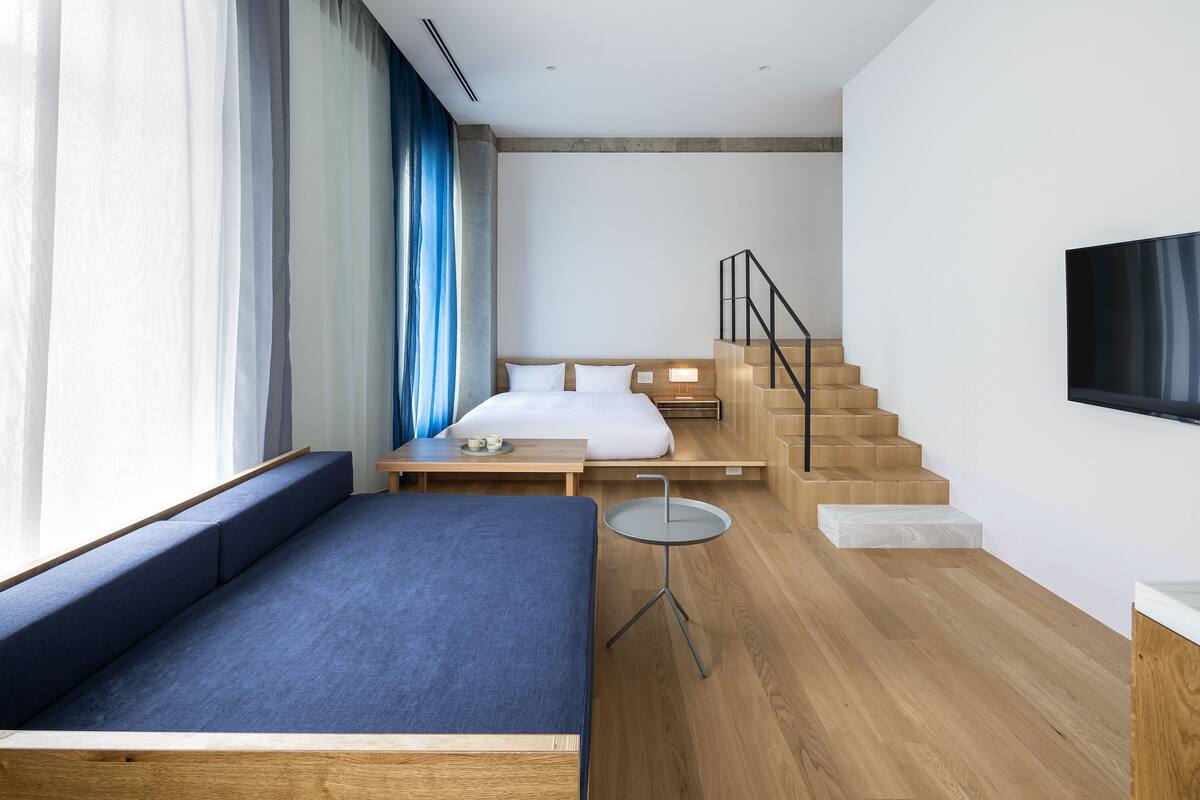 Ein modernes Hotelzimmer mit einem großen Bett, einer Sitzecke, einem kleinen Tisch und einer Treppe.