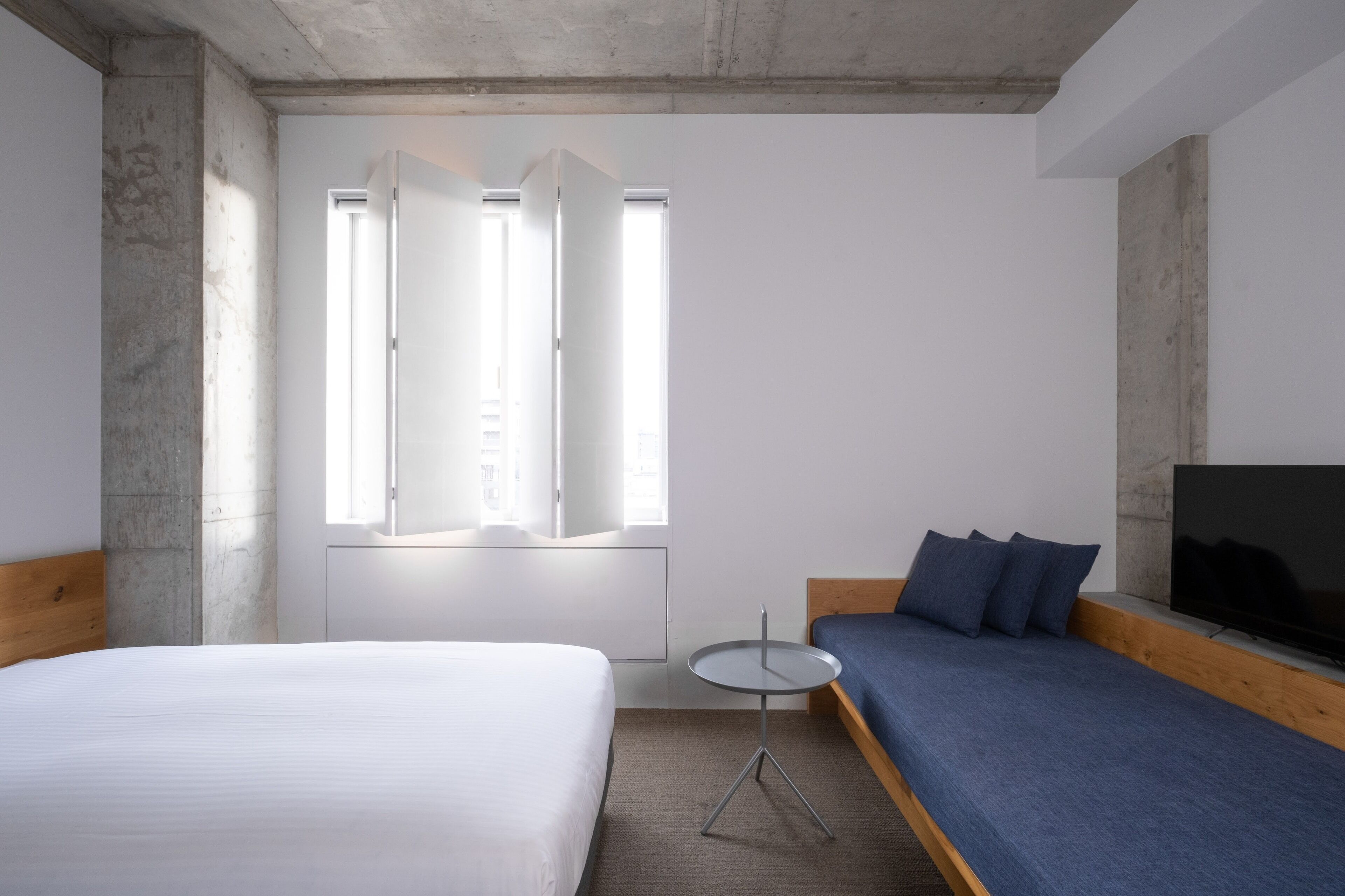 A modern hotel room with a large bed, a sofa, a small round table, and a TV.