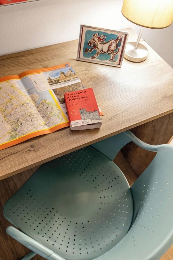 Una mesa de madera con un mapa, un libro titulado "Itinerario Arabo Normanno Mondiale" y una fotografía enmarco de un caballo.