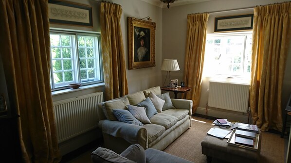 A cozy living room with a sofa, a table with books, and a window with curtains. - Nr Devizes, Marlborough & Bath, , walled garden (Seend)
