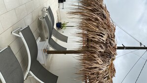 A seating area with a thatched structure, a potted plant, and a metal railing. - Gite corossol Martinique private pool, naturist residence (Sainte-Luce)