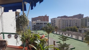 A residential area with multiple apartment buildings, a green sports field, and some potted plants.