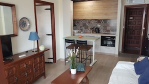 A compact living space with a dining area, kitchenette, and a TV on a wooden cabinet.