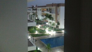 En vy över ett hotell med flera byggnader, en swimmingpool och väl upplysta gångvägar.