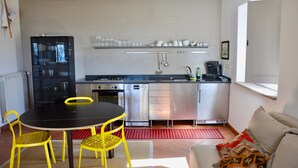 A compact kitchen with a dining table, chairs, and a coffee machine.